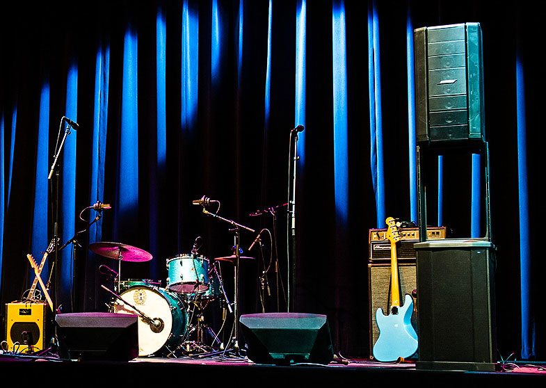 Intimate stage equipped with sound system, instruments and blue lighting